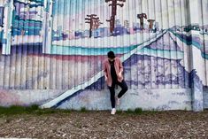 a woman standing in front of a wall with a mural on it's side