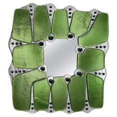 a green and silver decorative mirror with rivets on the edges, set against a white background