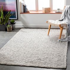 a living room area with a chair, window and rug on the floor in front of it