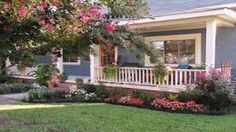 a blue house with flowers in the front yard