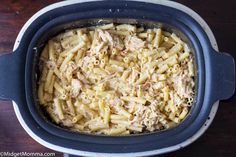 a casserole dish filled with pasta and chicken in a blue pot on a wooden table