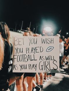 a group of people standing around each other holding a sign that says be you wish you played football as well as you play girls