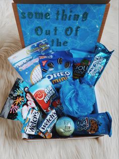 a box filled with candy and candies sitting on top of a white rug next to a sign