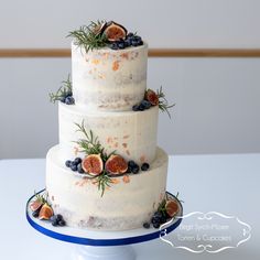 a three tiered cake with figs and blueberries on it