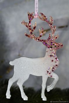 an ornament shaped like a deer with pink and purple glitters on its antlers