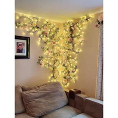 a living room filled with furniture covered in lights and flowers hanging from the wall next to a window