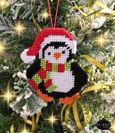 a cross stitch penguin ornament hanging from a christmas tree