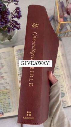 a person holding up a book with the words giveaway written on it in gold lettering