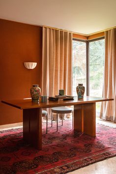 a dining room table with chairs and vases on it in front of an open window