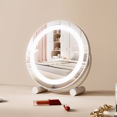 a round mirror sitting on top of a table next to a bottle and lipstick in front of it