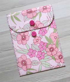 a pink and green flowered case with two buttons on the front, sitting on a wooden surface