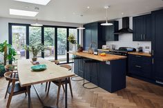 an open kitchen and dining area with blue cabinets, wood flooring and wooden table