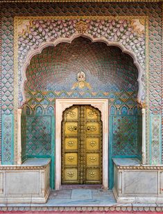 an ornate doorway with gold doors in the middle of a wall and steps leading up to it