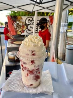 an ice cream sundae with whipped cream and strawberries on top sits under a tent