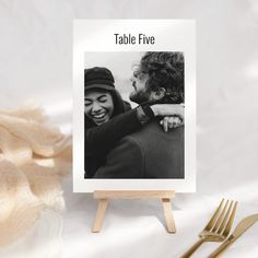 a couple is hugging each other in front of a table five sign with a gold fork next to it