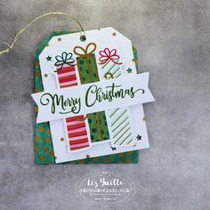 a christmas tag hanging from the side of a wall with presents on it and merry lettering