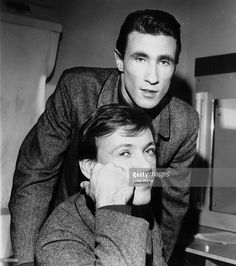 two men are posing for the camera in front of an oven, one is leaning on his head