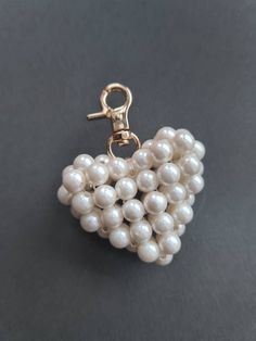 a white beaded heart shaped brooch on a gray surface with a gold clasp