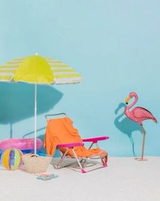 two beach chairs and an umbrella are sitting on the sand with toys in front of them