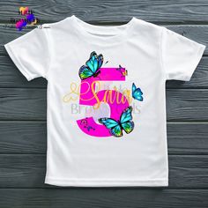 "Introducing our enchanting Butterfly Birthday T-Shirt, the perfect choice to make your little one's special day even more magical! This delightful shirt is designed to bring joy and beauty to your child's birthday celebration. 🦋 Design: The front of the t-shirt showcases a stunning and colorful butterfly's, fluttering gracefully around a vibrant birthday number. The butterfly's wings are adorned with intricate patterns and shimmering hues, creating a sense of wonder and elegance. Above the butterfly, in whimsical and celebratory font, it reads \"Your butterfly's name,\" adding a touch of enchantment to the design. 🎈 Key Features: Available in a range of sizes, ensuring a perfect fit for your child, from toddlers to pre-teens. Crafted from soft, high-quality fabric for comfort throughout Celebration Design, Number Design, Butterfly Birthday, Birthday Numbers, Kids Graphic Tees, Custom Cake Toppers, Colorful Butterflies, Butterfly Wings, Intricate Patterns