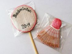 two lollipops in plastic bags with the word badminton written on them and an apple