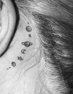 a woman's behind the ear tattoo with planets and stars