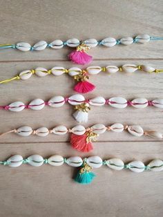 several seashells and tassels are arranged on a wooden table with beads