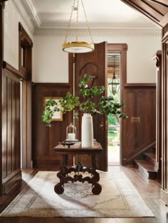 an entryway with wooden paneling and potted plants on a table in the center