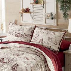 a bed with red and white comforter next to a christmas tree on the wall