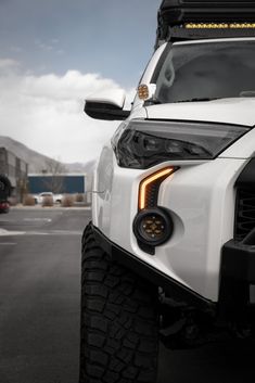 the front end of a white truck parked in a parking lot