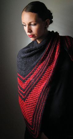 a woman wearing a red and black crocheted shawl in front of a dark background