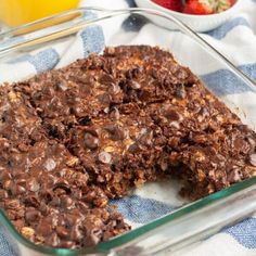 a glass dish filled with chocolate oatmeal bars and strawberries in the background