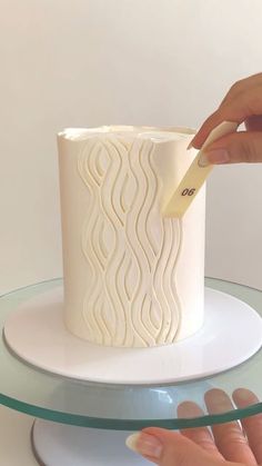 a woman is decorating a white cake with icing on the top and bottom