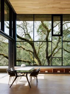 an open book showing a table and chairs in front of a window with trees outside