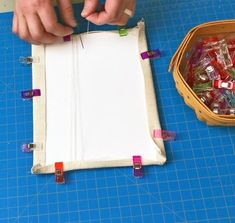 a person cutting up paper with scissors on a blue table next to a basket filled with candy