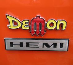 the emblem on an orange vehicle reads demon hemi