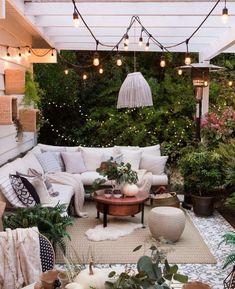 an outdoor living room with lots of plants and lights