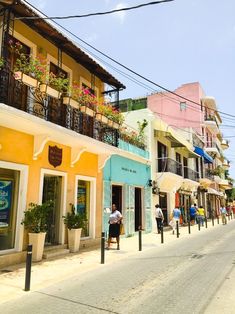 people are walking down the street in front of colorful buildings with balconies on them