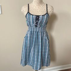 New Without Tags. Adorable Sun Dress With Ruffled And Button Detail On Bodice. Plaid Pattern With White, Black, Turquoise And Blue Metallic Stripes. 100% Cotton 2 Front Pockets With Ruffle Detail Ruched Elastic Waist To Adjust For Fit. Fully Lined - 100% Polyester Purchased At Francesca’s Approx Measurements Armpit To Armpit Laying Flat - 12.5” Length Down Front Center - 26” Black Turquoise, Sun Dress, Button Detail, Plaid Pattern, Sundress, Bodice, White Black, Dresser, Elastic Waist