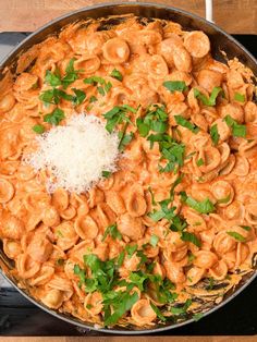 a skillet filled with pasta and sauce covered in parmesan cheese sprinkled with parsley