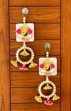 two pairs of earrings hanging on a wooden door with beads and flowers in the center