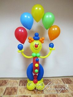 a clown with balloons in the shape of a ballon on top of a wooden floor