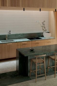 a large kitchen with wooden cabinets and counter tops, along with two bar stools