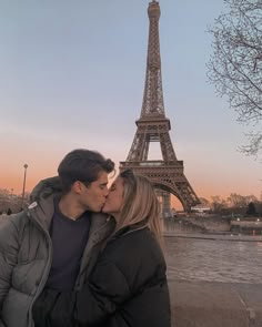 a man and woman kissing in front of the eiffel tower, paris france