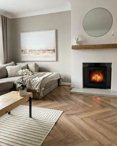 a living room filled with furniture and a fire place next to a window on top of a hard wood floor