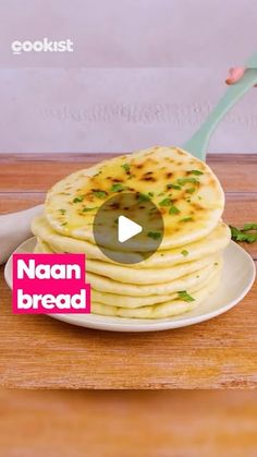 a person holding a spoon over a stack of pancakes on a plate with the words naan bread