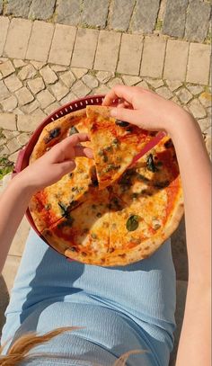 a person holding a pizza in front of their face with one slice taken from it