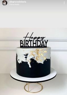 a black and white birthday cake with gold foiling on the top that says happy birthday