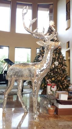 a christmas tree in the middle of a living room with a deer statue next to it