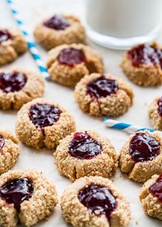 cookies with jam are arranged on a table next to a glass of milk